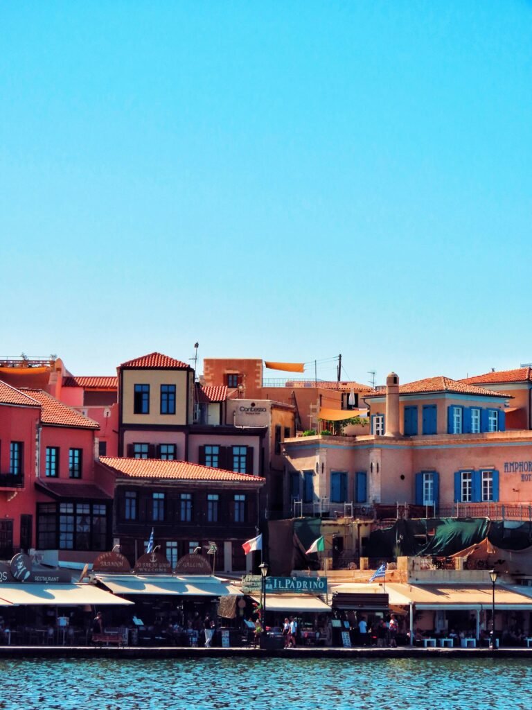 Charming view of the colorful Venetian harbor buildings in Chania, Greece against a clear blue sky.